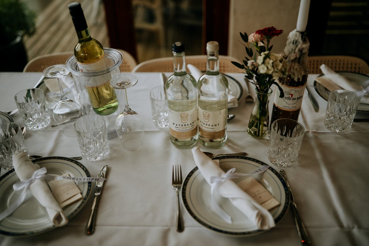 Festlich gedeckte Tafel mit Waterkant-Mineralwasser und Namenskärtchen bei der Hochzeitsfeier von Stina und Delf