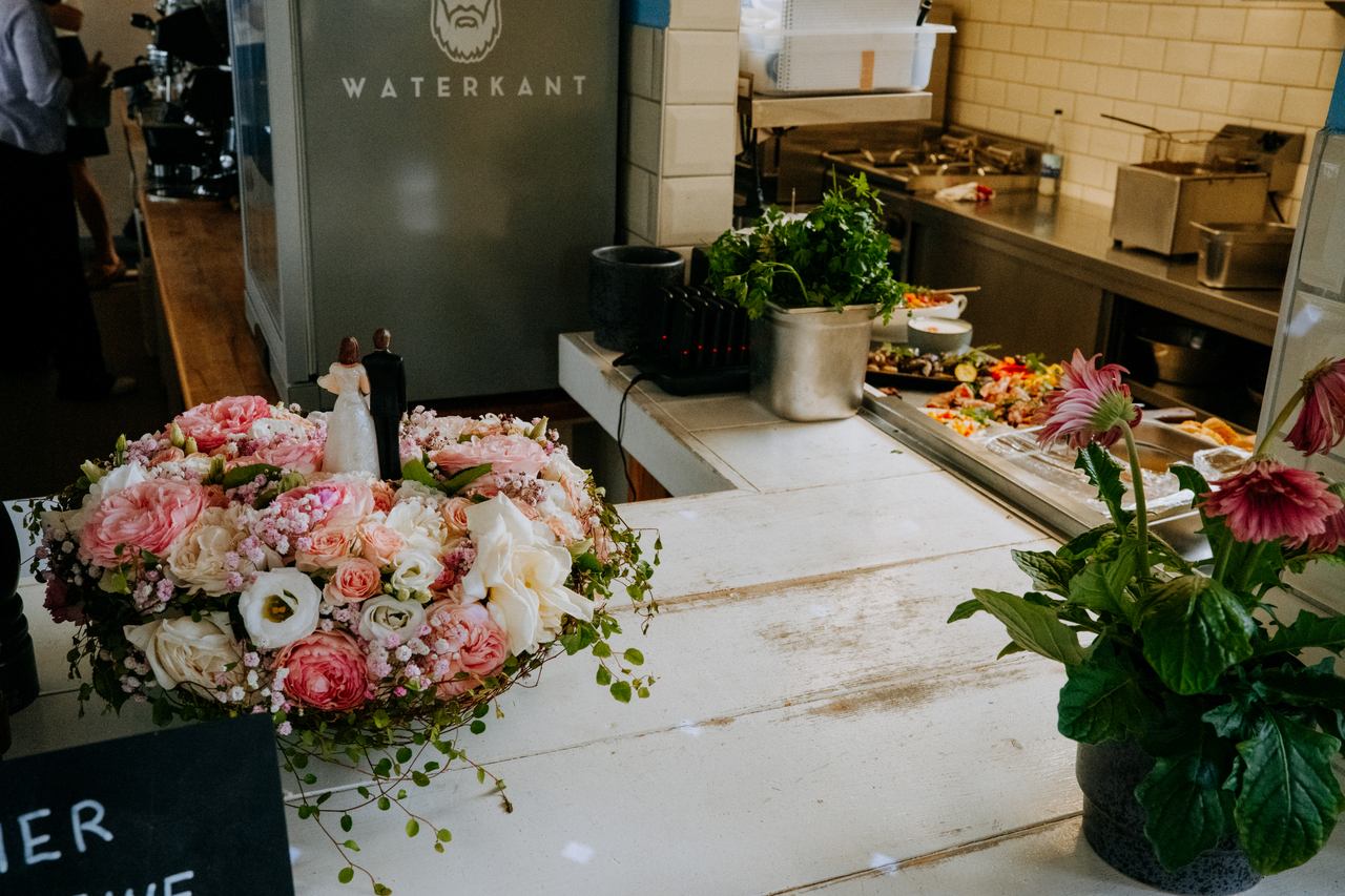 Blumenkranz mit Brautpaar-Figuren am Buffet der Strandlocation Ute im Bikini