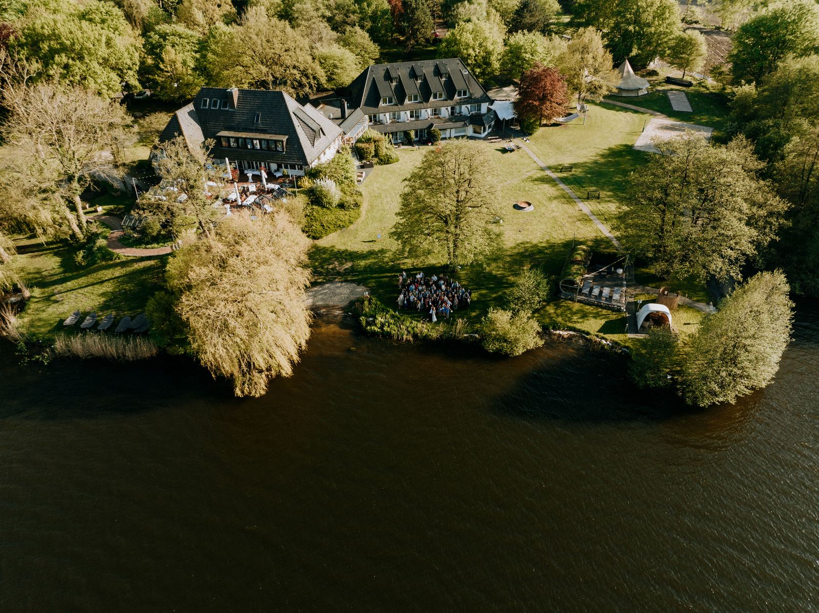 Drohnenaufnahme vom Töpferhaus am Bistensee mit Gruppenfoto der Hochzeitsgesellschaft am Ufer
